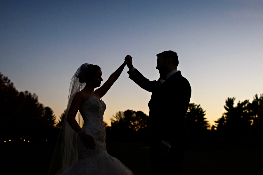 A wedding couple high five in the sunset.